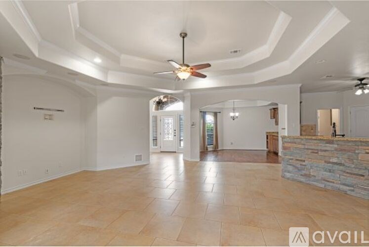 A spacious room with a fan and a stone wall.