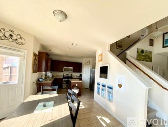 A kitchen with a dining table and chairs is visible from the stairs.
