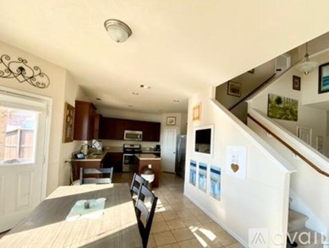 A kitchen with a dining table and chairs is visible from the stairs.