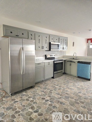 A kitchen with a refrigerator, oven, microwave, and dishwasher.