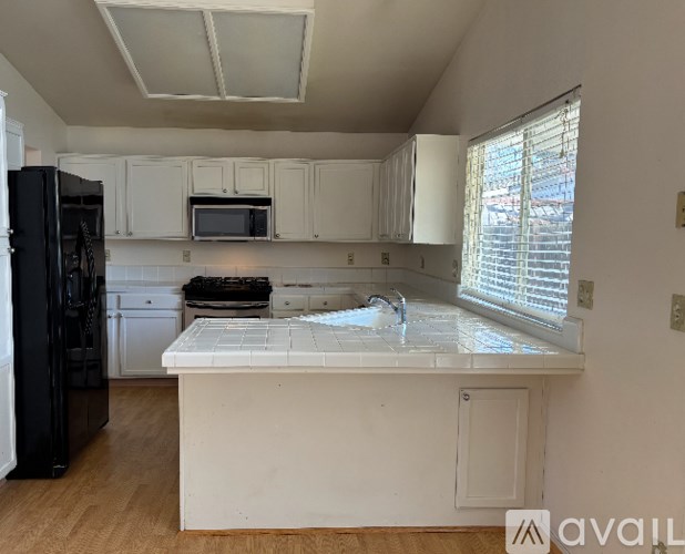 A kitchen with white cabinets and a black refrigerator.