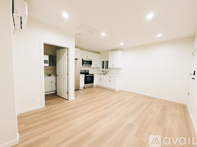 A spacious kitchen with wooden flooring and white walls.