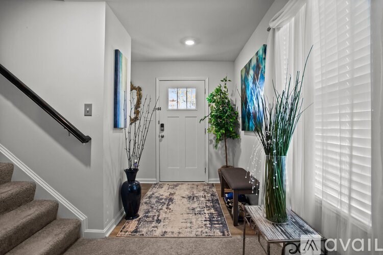 A hallway with a staircase, a bench, and a painting on the wall.