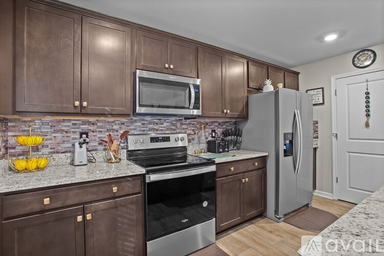A kitchen with brown cabinets and a stainless steel refrigerator.