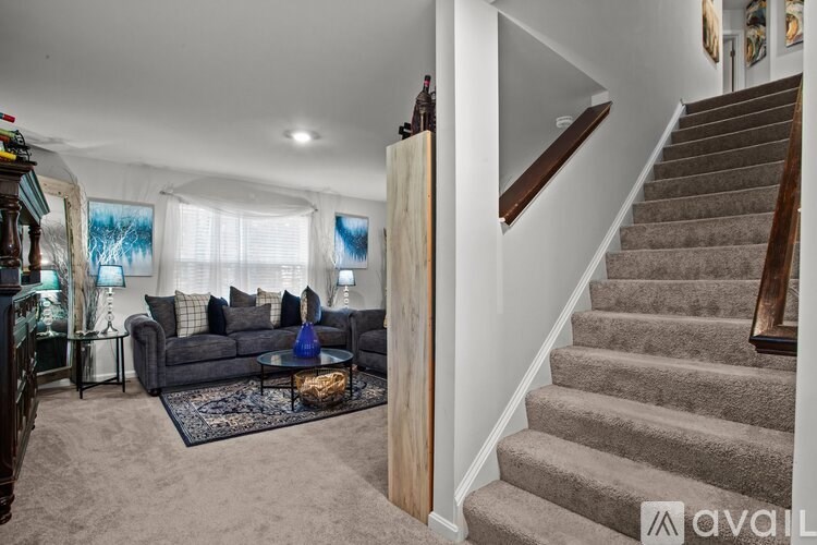 A living room with a grey couch and a staircase.