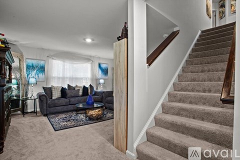 A living room with a grey couch and a staircase.