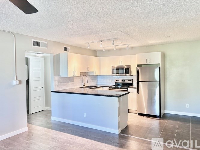 A kitchen with white cabinets and a black countertop.