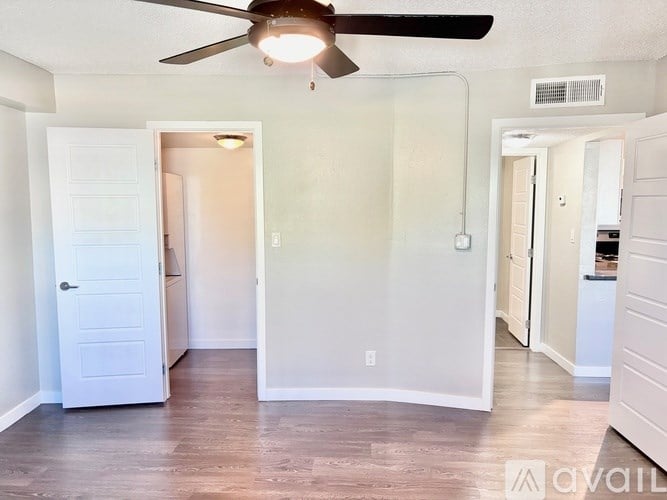 A room with a ceiling fan and a door leading to another room.