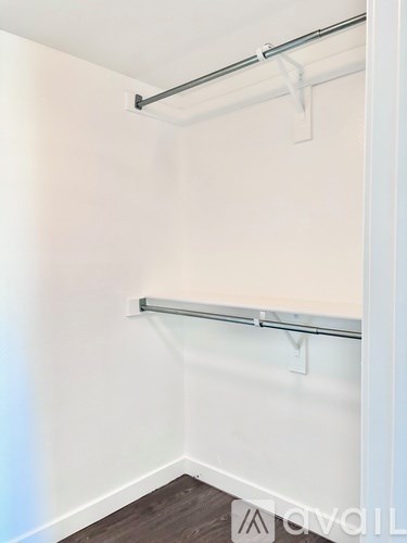 A white wall with a grey metal rod and white hooks.