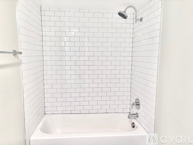 A white tiled shower with a white bathtub and a shower head.