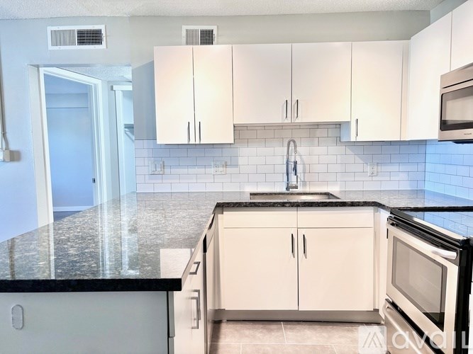 A kitchen with black granite countertops and white cabinets.