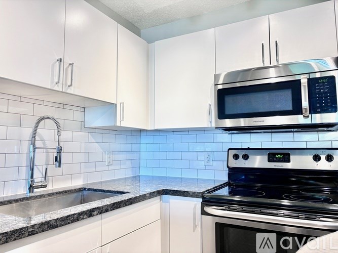 A kitchen with a stove, sink, and cabinets.