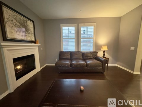 A living room with a fireplace, a brown couch, and a painting on the wall.