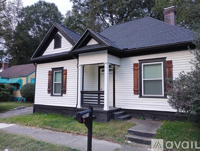 A white house with a black roof and a mailbox in front.