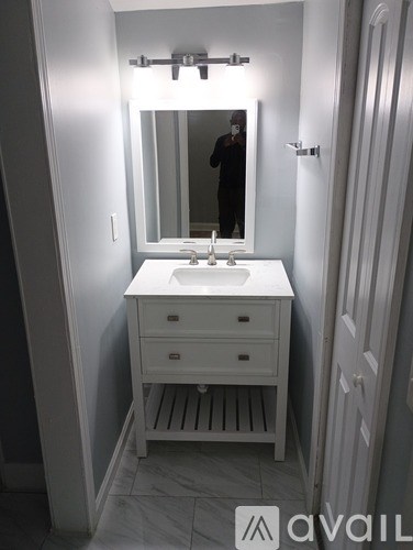 A white bathroom vanity with a mirror above it.