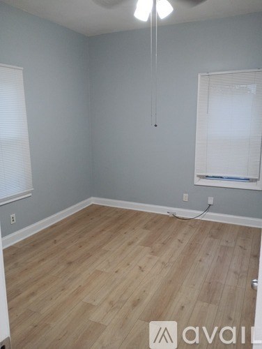 A room with wooden flooring and a window with blinds.