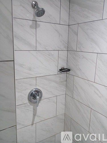 A shower head and faucet in a tiled bathroom.