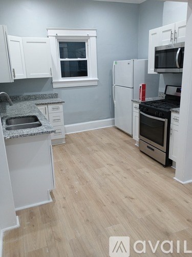 A kitchen with white cabinets and a wooden floor.