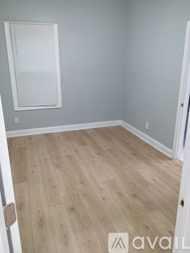 A room with wooden flooring and a window with blinds.