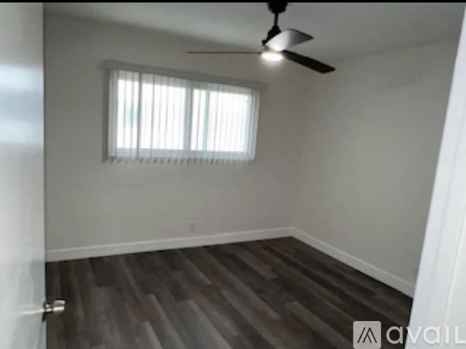 A room with a ceiling fan and a window with blinds.