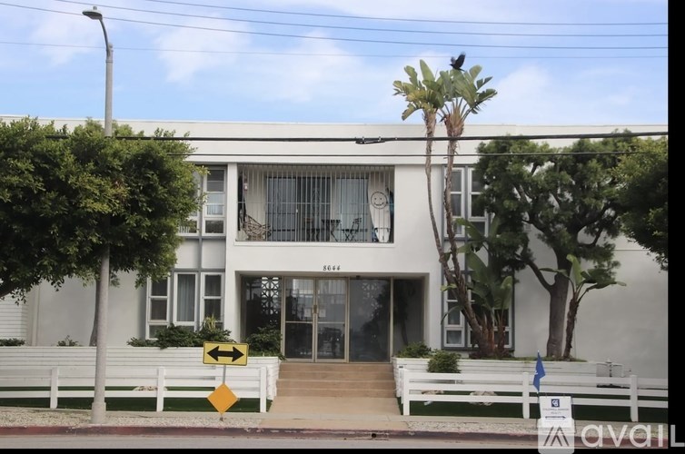 A white building with a yellow sign in front of it.
