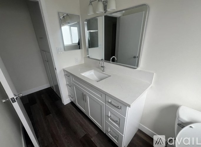 A white bathroom vanity with a sink and mirror.
