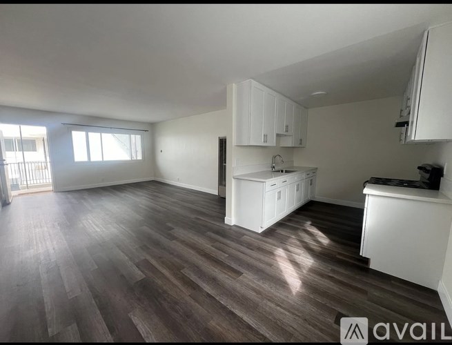A kitchen with white cabinets and a wooden floor.