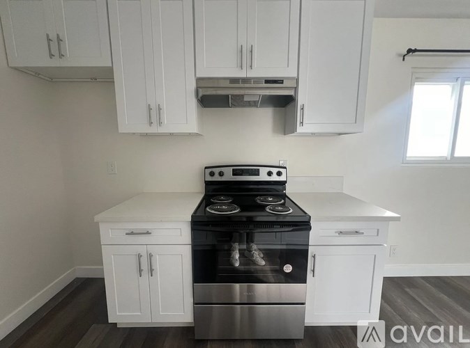 A kitchen with white cabinets and a stove top oven.