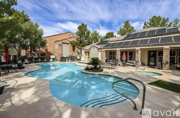 A large outdoor swimming pool with a slide and a patio area with chairs and a table.