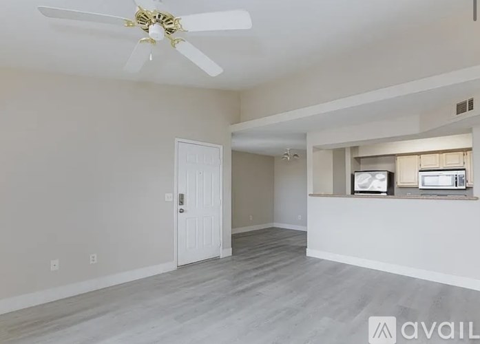 A spacious living room with a ceiling fan and a door leading to another room.