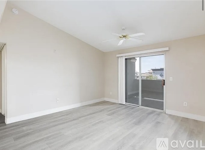 A spacious room with a ceiling fan and sliding glass doors.