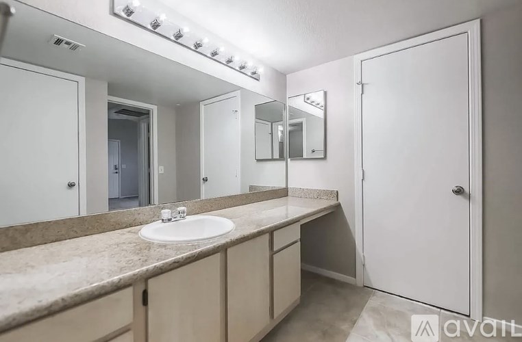 A bathroom with a sink, mirror, and lighting fixture.