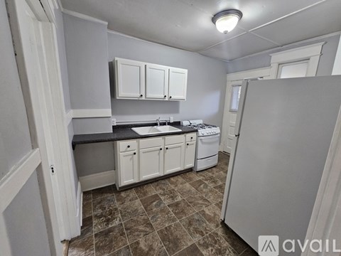 A kitchen with white cabinets and a tiled floor.