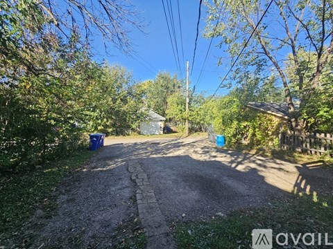 A gravel path leads through a lush green area with trees and bushes on either side.