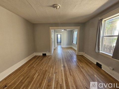 A room with wooden flooring and a doorway leading to another room.