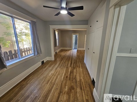 A long hallway with wood floors and a ceiling fan.