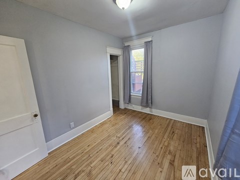 A room with wooden flooring and a window with curtains.