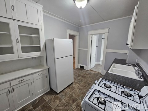 A kitchen with a white refrigerator, white cabinets, and a white stove top oven.