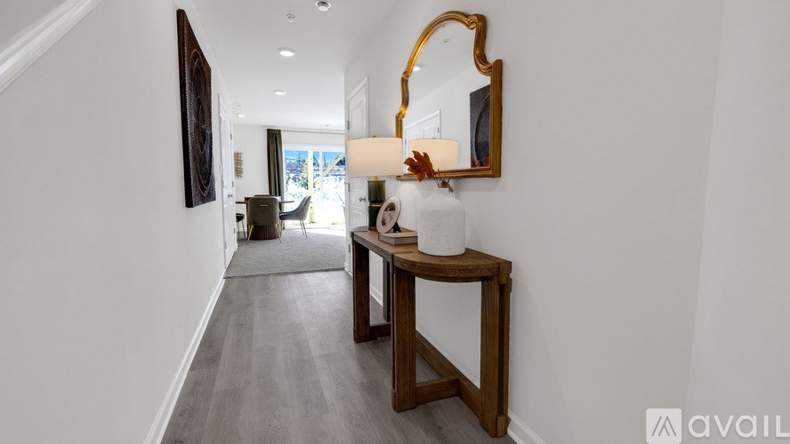 A hallway with a mirror and a table with a vase on it.