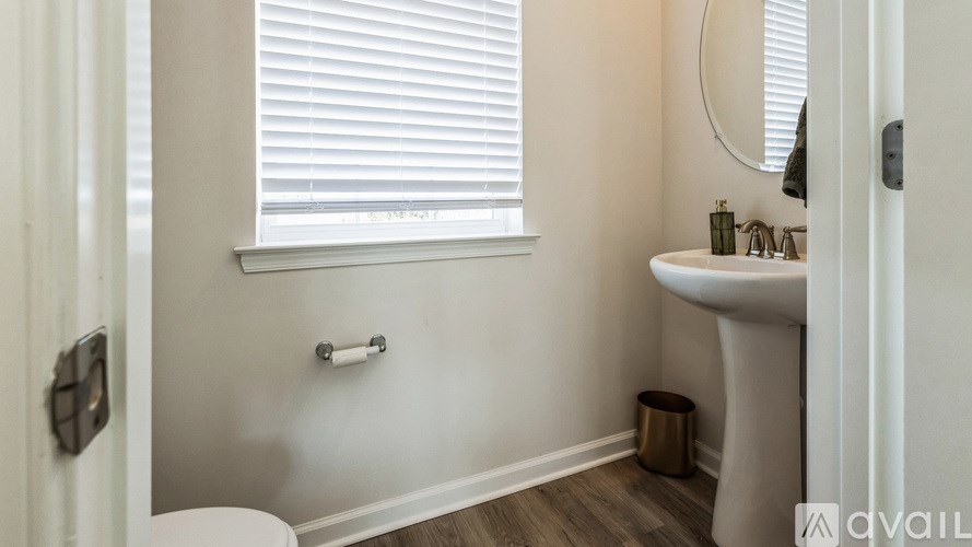 A white bathroom with a toilet, sink, and window.
