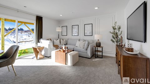 A living room with a grey sofa, a wooden cabinet, and a television on the wall.