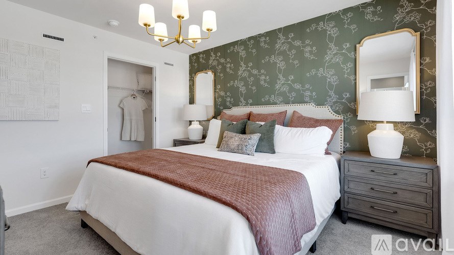 A bedroom with a large bed, a chandelier, and a mirror on the wall.