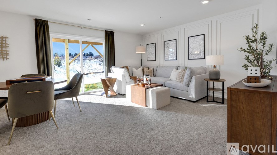 A living room with a grey sofa, a wooden cabinet, and a grey carpet.