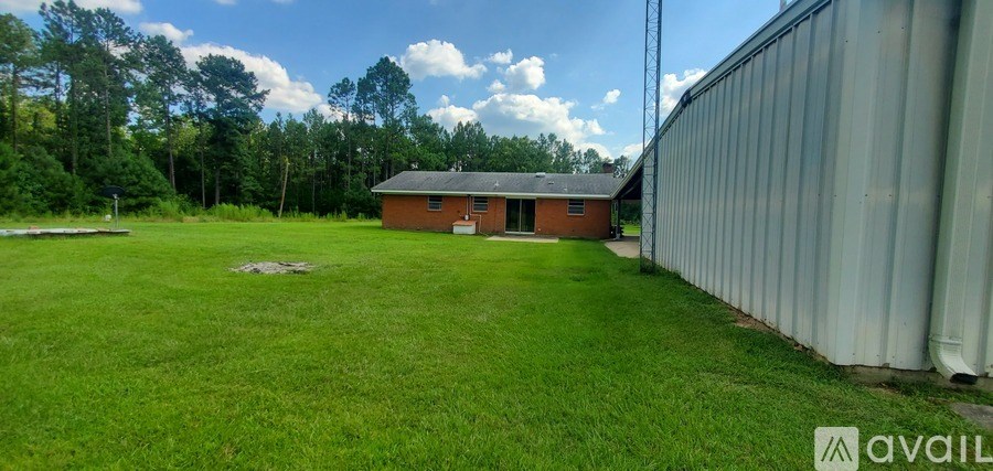 A grassy field with a building and a fence in the background.