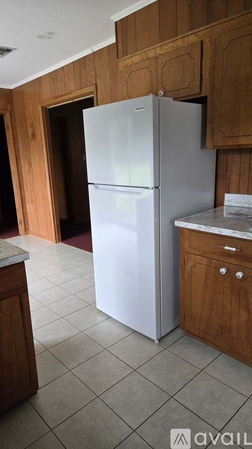 A white refrigerator in a kitchen with wooden cabinets.