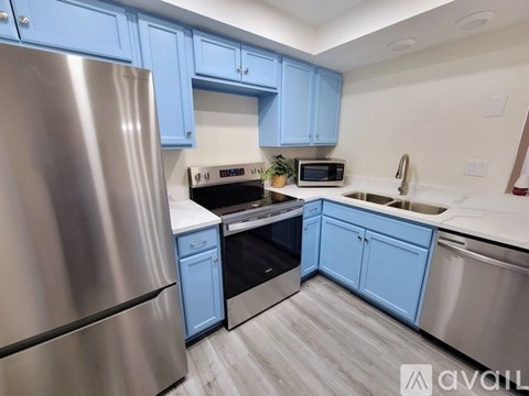 A kitchen with blue cabinets and stainless steel appliances.