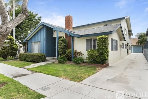 A house with a blue roof and a white wall is for sale.