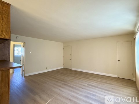 A spacious room with wooden flooring and white walls.