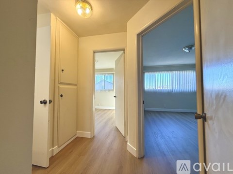 A hallway with a door on the right and a mirror on the wall.