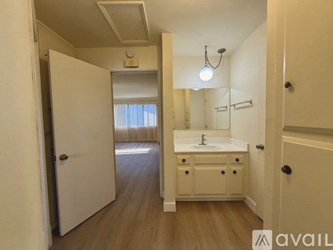 A bathroom with a sink, mirror, and wooden floors.